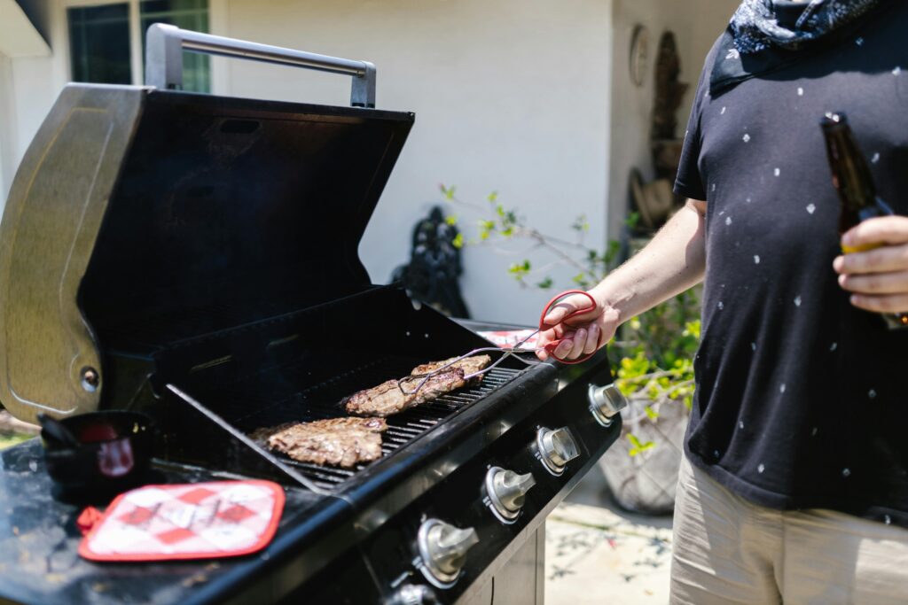 A white man grilling up some meat on a standalone bbq grill in Bradenton, FL